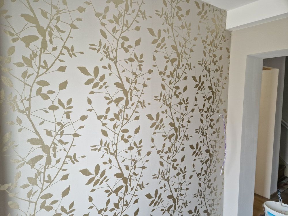 Beige Wand mit goldenen Blätterranken in einem modernen Raum mit heller Atmosphäre