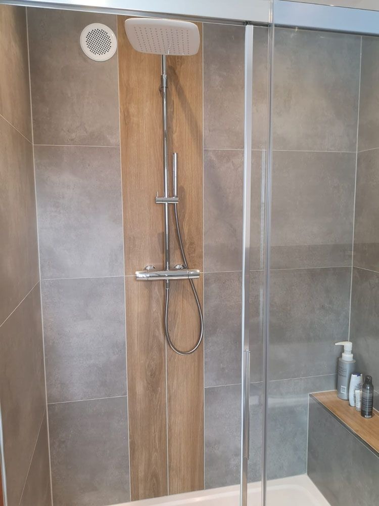 Moderne Dusche mit grauen und holzfarbenen Fliesen sowie silberner Armatur
