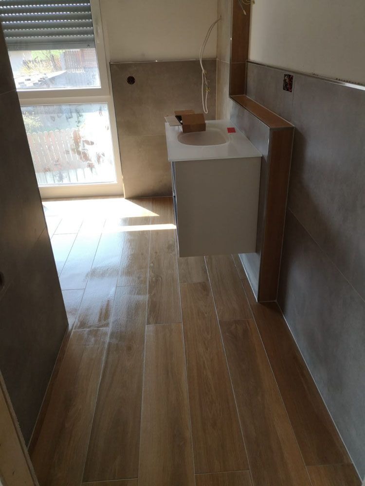Neues Badezimmer mit großer Fensterfront, Holzoptikfliesen und modernem Waschbecken