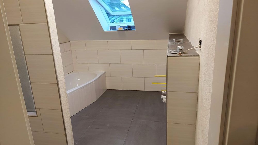 Helles Bad mit Dachfenster und Eckbadewanne sowie grauen Bodenfliesen