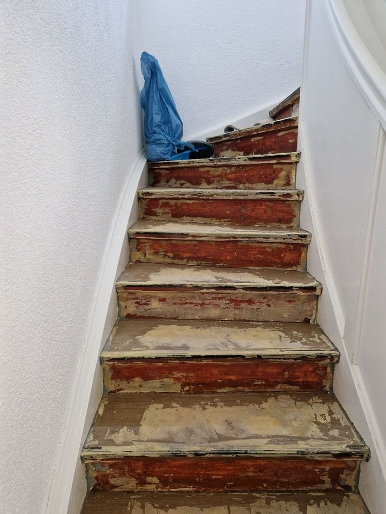Eine alte Holztreppe mit abgenutzten Stufen und einer blauen Jacke am oberen Ende